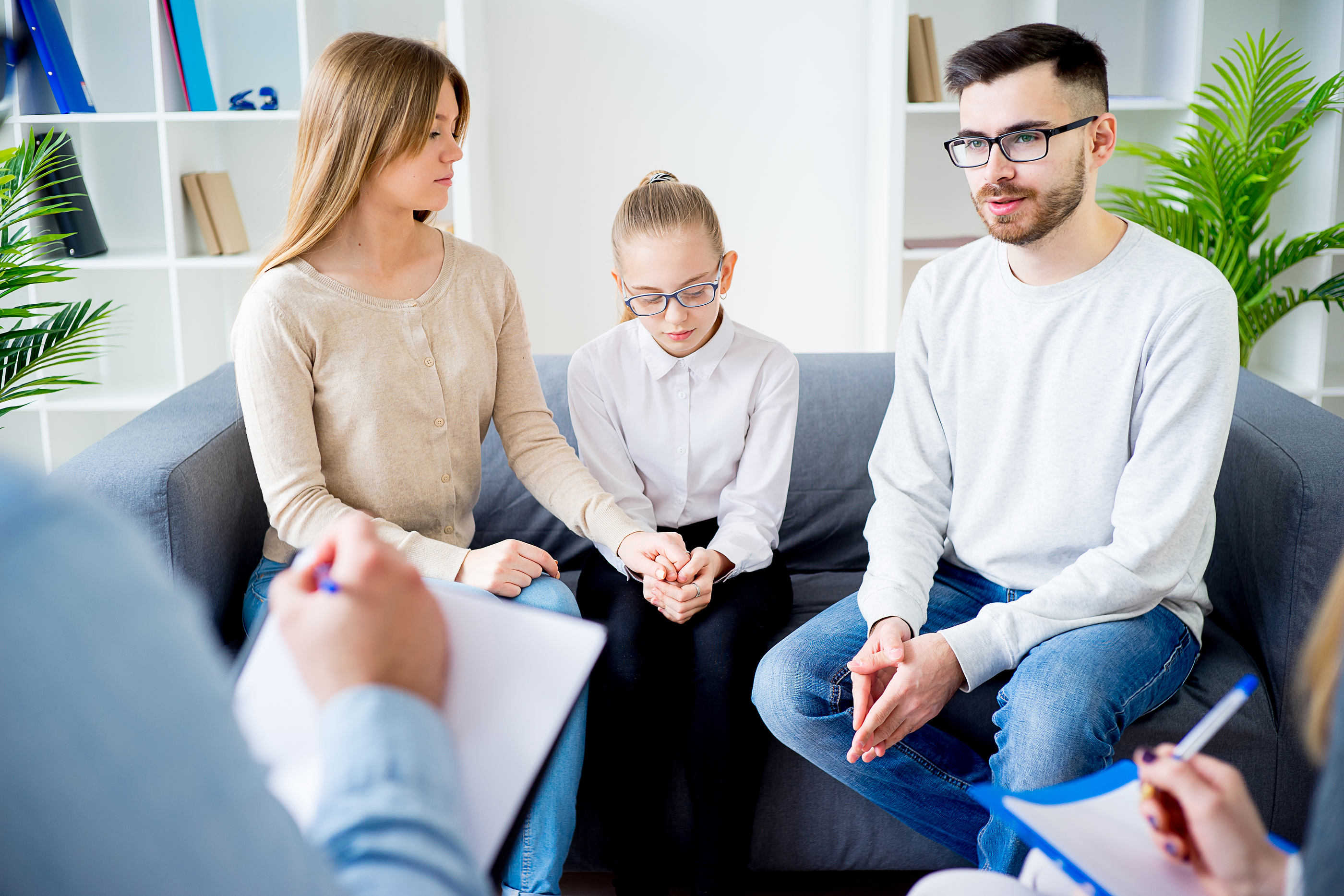 Family of three talking with psychologist. Psychologist taking notes.
