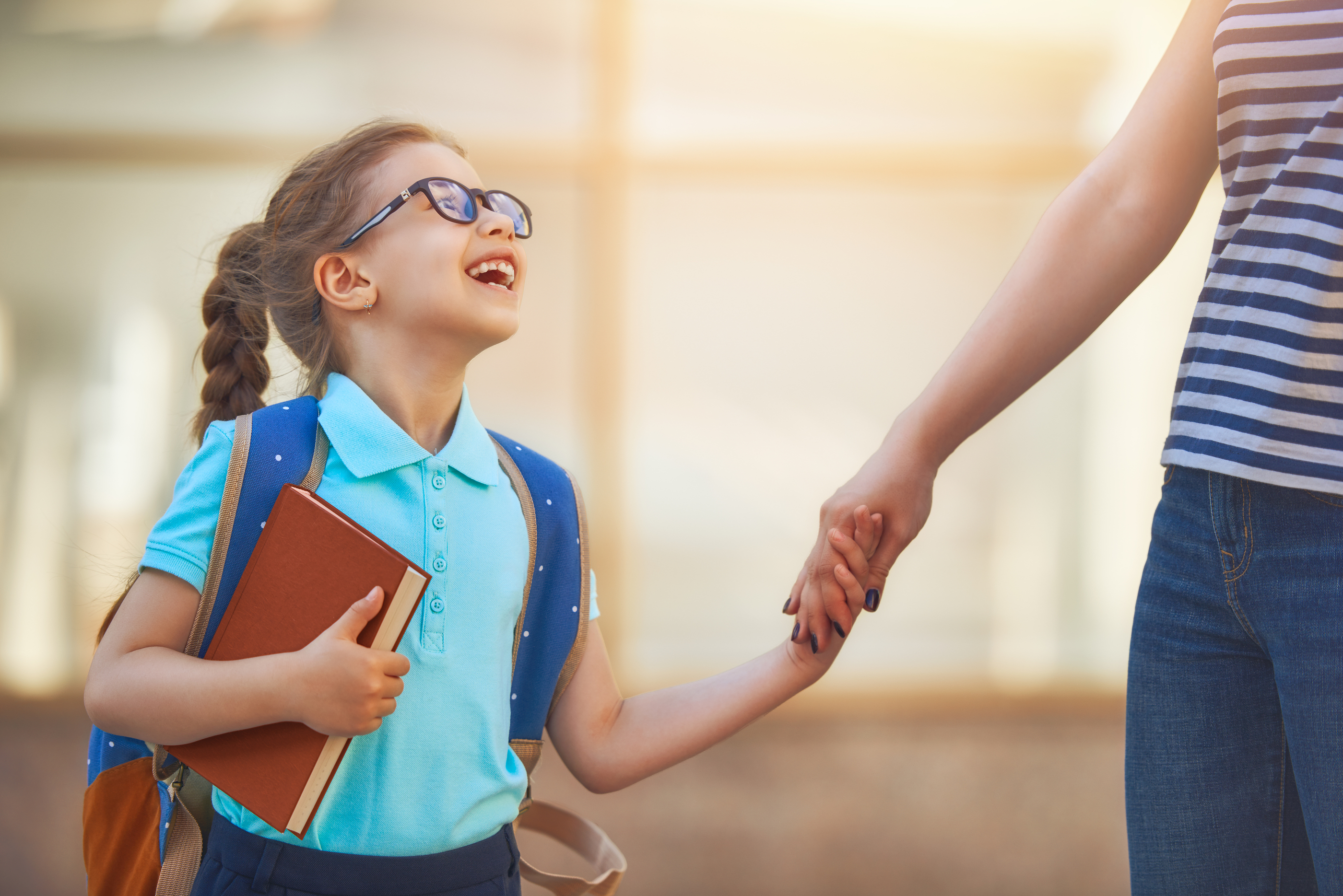 Parent and pupil of primary school go hand in hand. Woman and gi